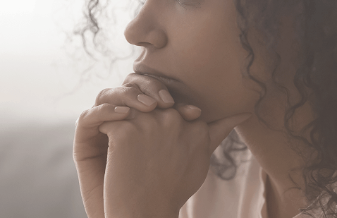 Close-up of a pensive woman with hands on her chin, representing deep reflection and emotional concern about health