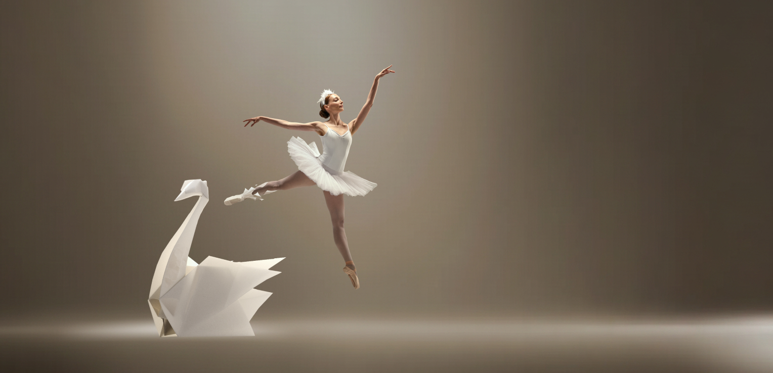 Ballerina performing a jump next to a large origami swan structure, symbolizing physical lightness and freedom of movement